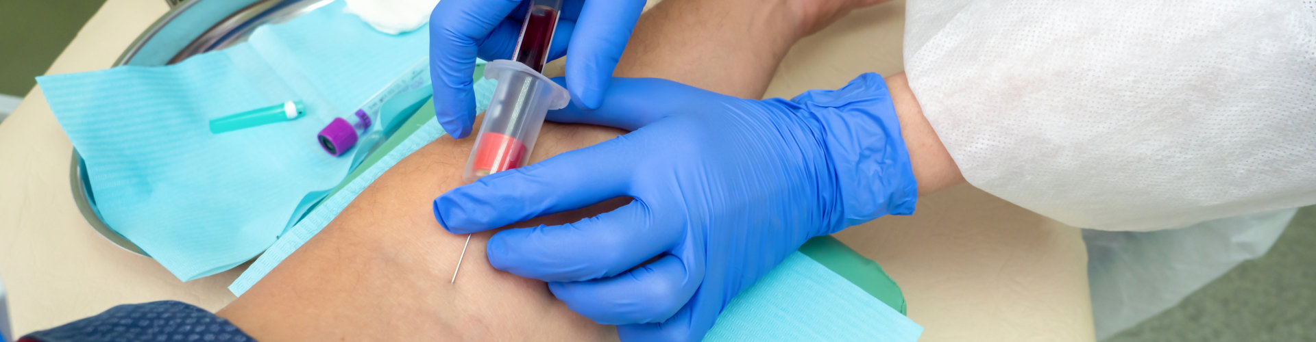 phlebotomist extracting blood sample from patient